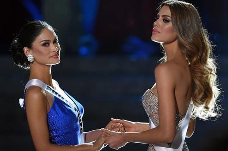 Miss Filipijnen (l) en Miss Colombia houden hun handjes vast vlak voordat ze de eerste, foutieve uitslag vernemen.