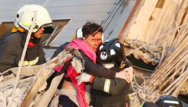 Спасатели помогают мужчине, пострдавшему во время землетрясения на Тайване, 6 февраля 2016