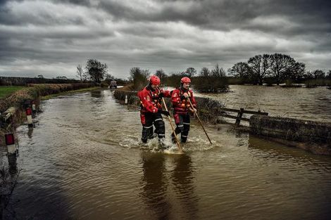 Brandweermannen peilen de waterstand rond de brug bij Tadcaster, die gedeeltelijk is bezweken onder het woeste water.