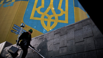 Женщина проходит мимо огромного украинского флага в центре Киева